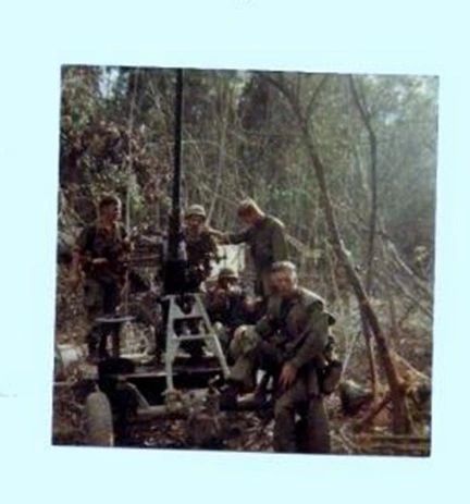 A group of men standing next to a machine gun.